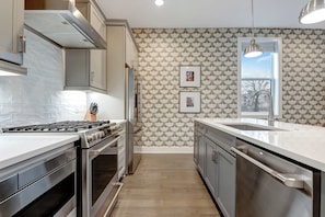 Una cocina moderna con electrodomésticos de acero inoxidable, un salpicadero de azulejos y una pared con estampado.