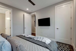 Un dormitorio con una cama, un televisor montado en la pared y una alfombra estampada en el suelo.
