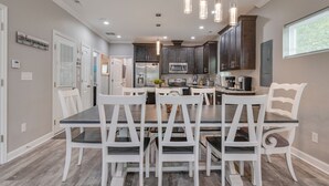 Una cocina moderna con armarios oscuros, una isla central e iluminación colgante.