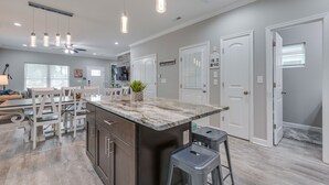 Una cocina moderna con encimera de mármol, luces colgantes y ventilador de techo.