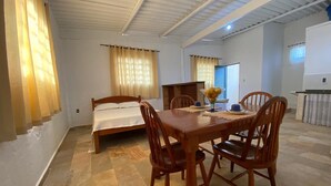 A room with a bed, a dining table with chairs, and a kitchenette area. - Loft das Águas (MG)