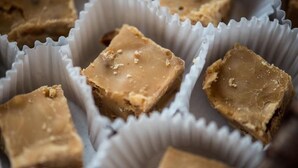 Several square-shaped, caramel-colored fudge pieces in paper cups. - Loft das Águas (MG)