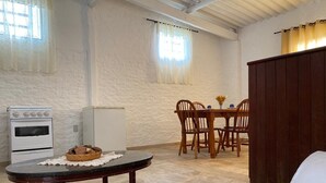 A room with a dining table, chairs, a small refrigerator, and a sofa. - Loft das Águas (MG)