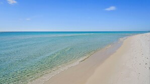 Een strand met helder turquoise water en een zandstrand.