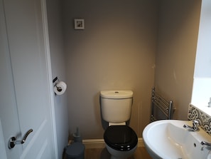 A bathroom with a toilet, sink, and a small trash bin. - The Cambus Flat, Cambuskenneth, Stirling (Stirling)