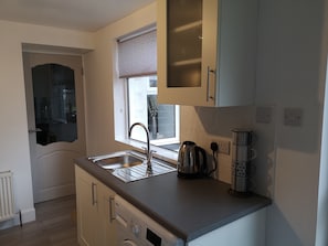 A compact kitchen with a sink, kettle, and a built-in oven.