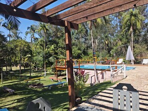 A pool area with a wooden pergola, a pool table, and outdoor seating. - RECANTO DO PÁSSAROS ***with heated pool*** heated year-round.   (Socorro)