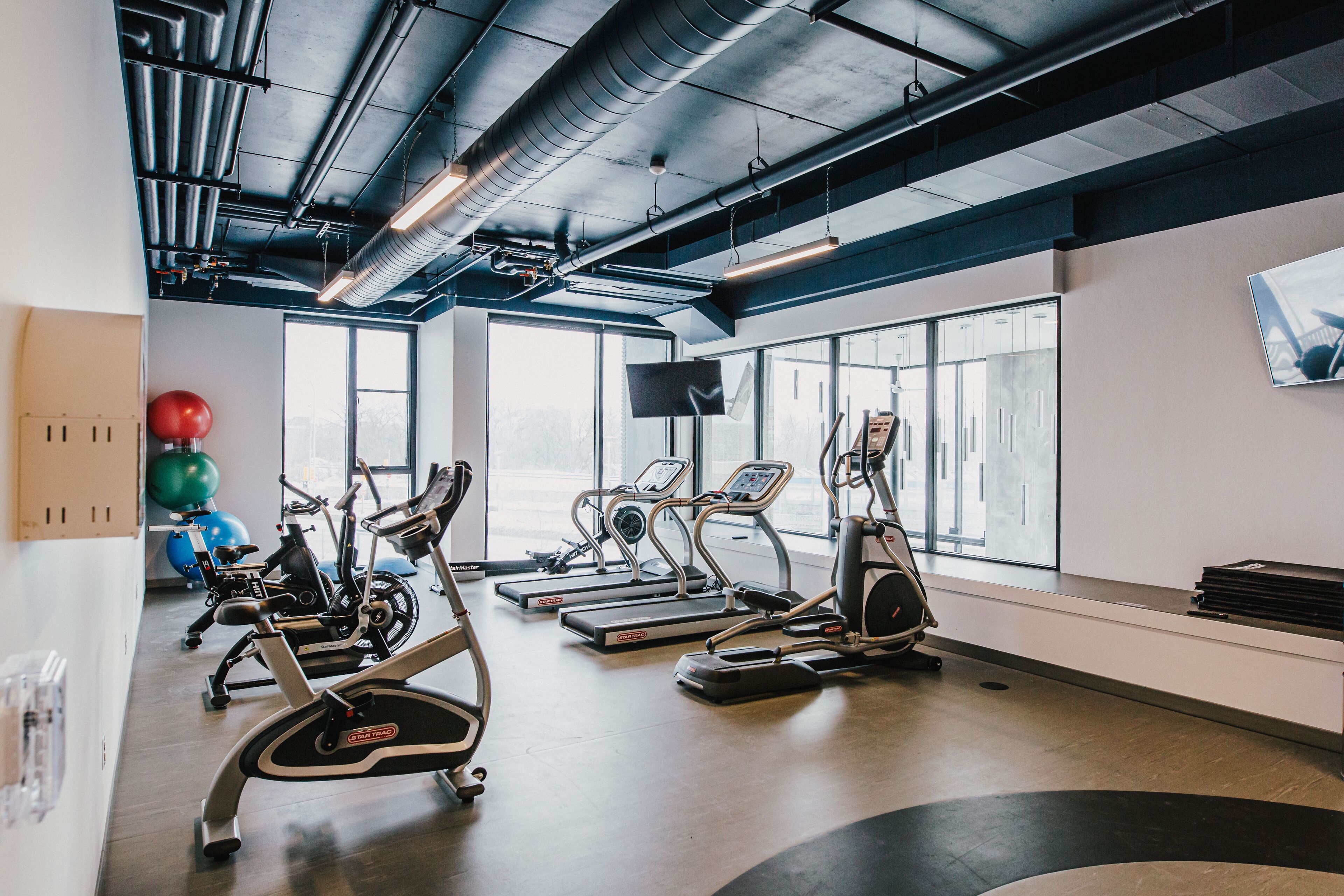 A gym with treadmills, elliptical machines, and exercise balls.