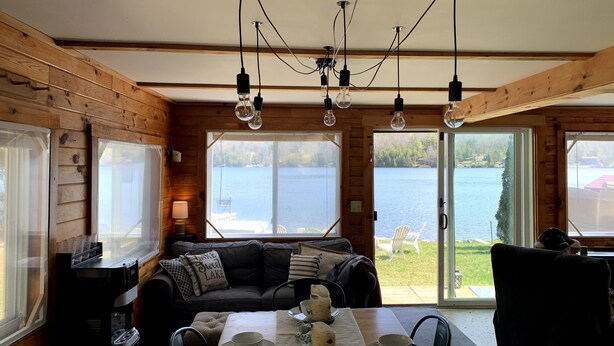 A cabin with a dining table set for four, a sofa, and a view of a lake. - on gorgeous Great Pond (lake), great for families!  (Belgrade)