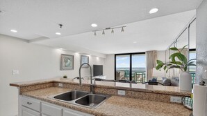 Eine moderne Küche mit Granit Arbeitsplatten, Spüle aus Edelstahl und weißen Schränken.