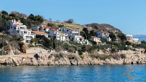 A coastal residential area with multi-story houses, a rocky shoreline, and a clear blue sea. - Lori Red - Cozy Hideaway for Two with sea view 🌊 (Baška)