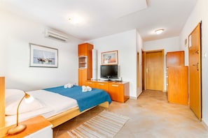 Une chambre d’hôtel comprenant un lit, un bureau avec une lampe, une télévision et une armoire.