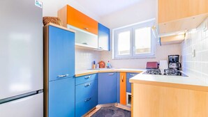 A compact kitchen with a refrigerator, cabinets, a stove, and a window. - Ema - Cozy Pet-friendly Suite for Two with Parking (Baška)
