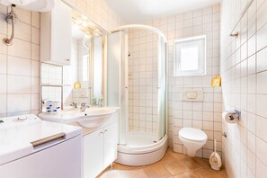 Ein Badezimmer mit Dusche, Toilette, Waschbecken und Spiegel.