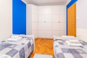 Una habitación con dos camas, un armario y una puerta de madera.