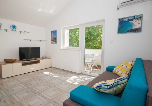 A living room with a television, a sofa, and a dining area with chairs.