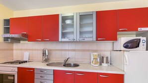 Een moderne keuken met rode kastjes, een roestvrijstalen spoelbak, een koffiezetapparaat en een magnetron.