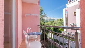 Een balkon met een tafel en stoelen, een uitzicht op een berg en een gebouw met airconditioning.