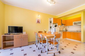 A compact living space with a dining area, kitchenette, and a television on a wooden cabinet. - Apartment Nada 2 with air condition and wifi internet (Baška)