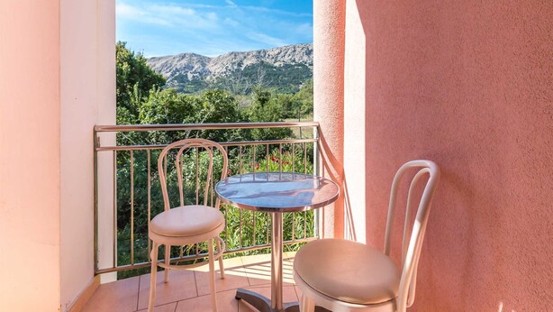 A balcony with two chairs and a small table, offering a view of mountains and greenery. - Apartment Nada 2 with air condition and wifi internet (Baška)