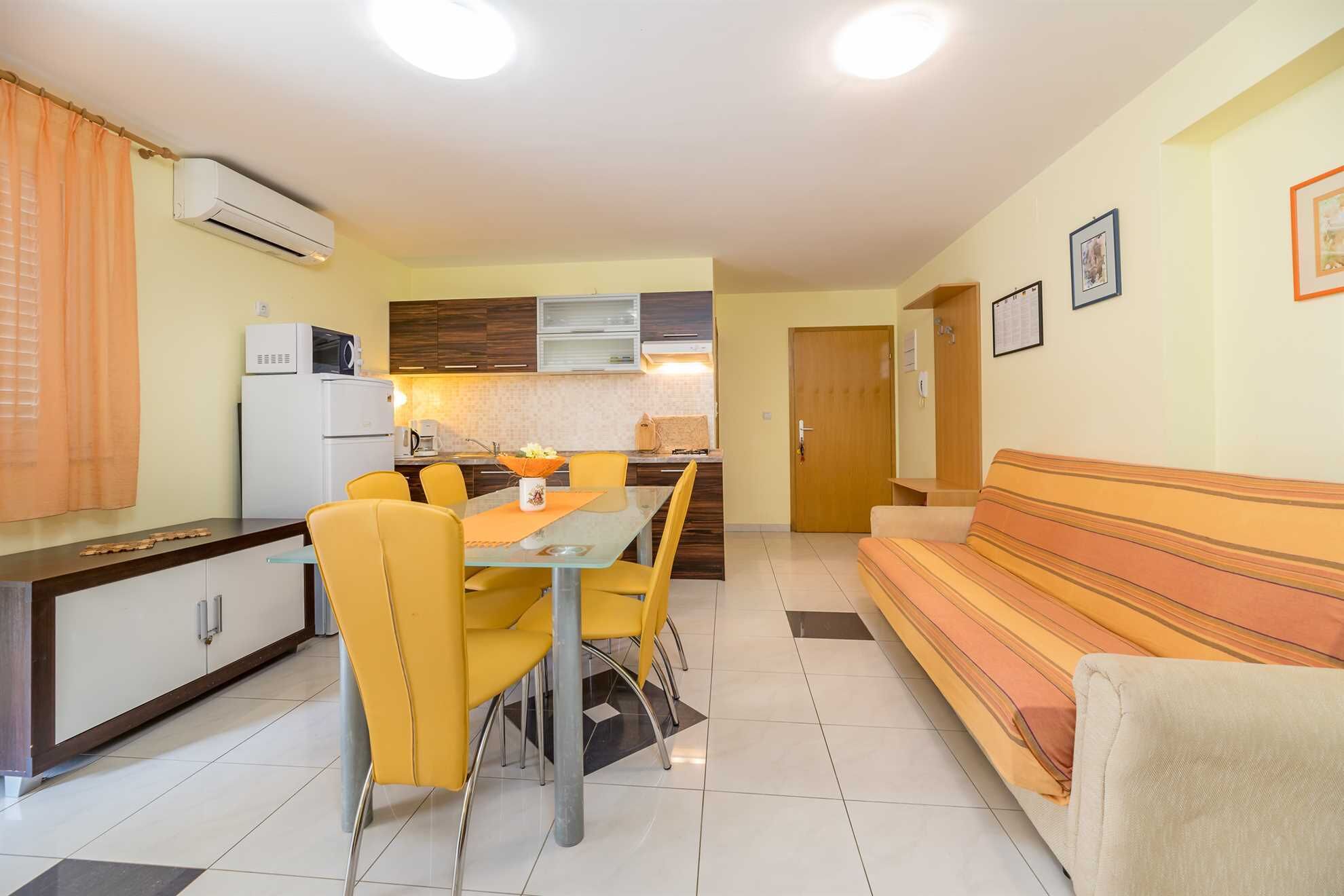 A compact living space with a dining area, kitchenette, and a sofa.