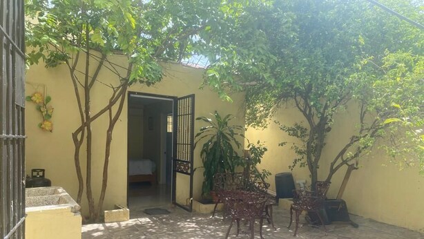 A courtyard with a tiled floor, a bed, a table with chairs, and potted plants. - Nido del patio, 40 min playa boca chica y 5 min centro de ciudad (Santo Domingo, Este)