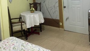 A room with a bed, a table with a basket of flowers, a chair, a television mounted on the wall, and a door. - Nido del patio, 40 min playa boca chica y 5 min centro de ciudad (Santo Domingo, Este)