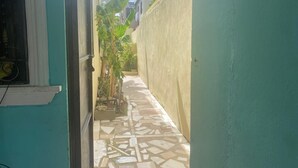 A narrow alleyway with a tiled floor, a green wall on one side, and a window on the other. - Nido del patio, 40 min playa boca chica y 5 min centro de ciudad (Santo Domingo, Este)