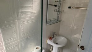 A bathroom with a toilet, a sink, and a glass shower enclosure. - Nido del patio, 40 min playa boca chica y 5 min centro de ciudad (Santo Domingo, Este)