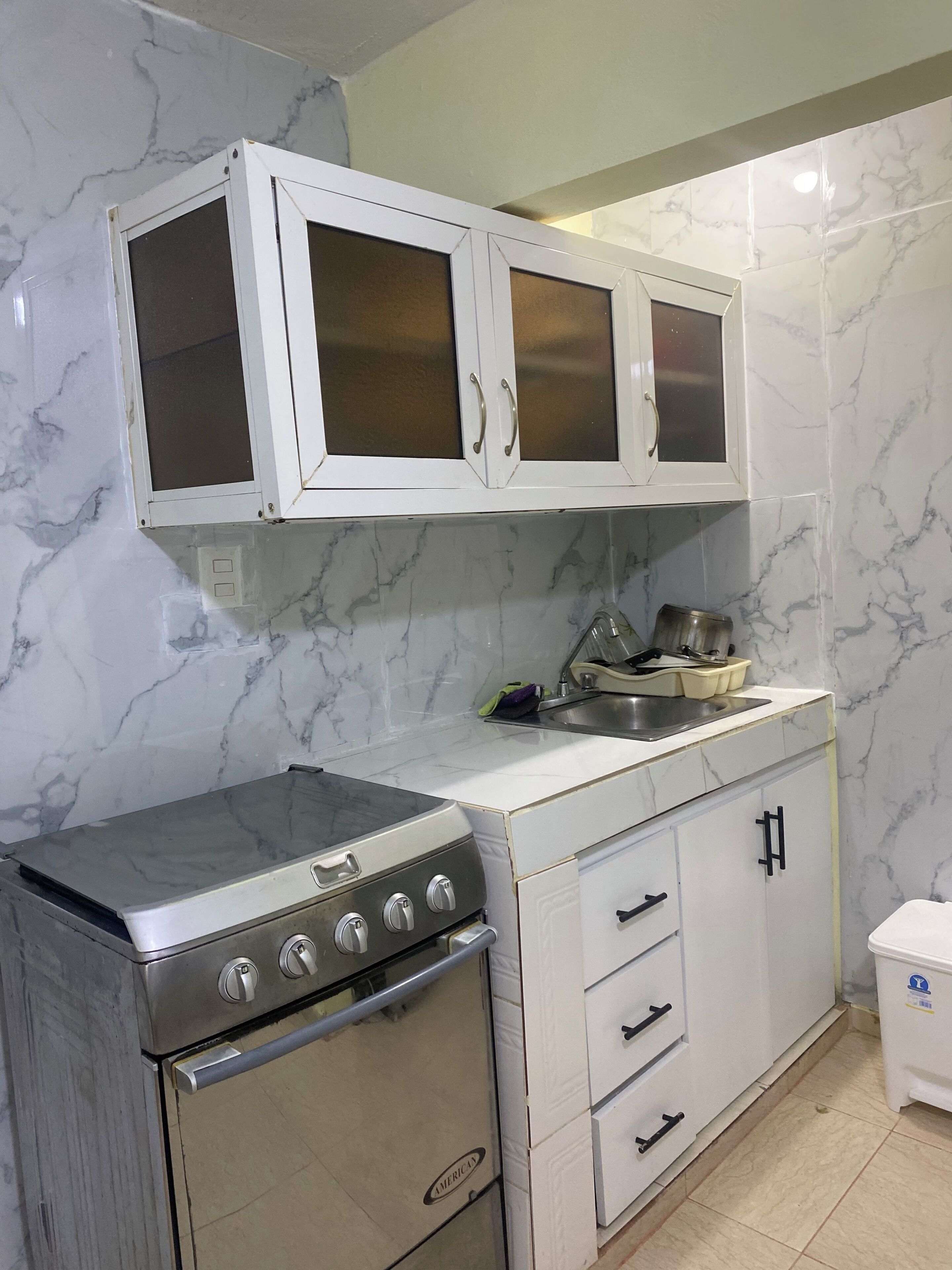 A kitchen with white cabinets, a stove, and a sink.