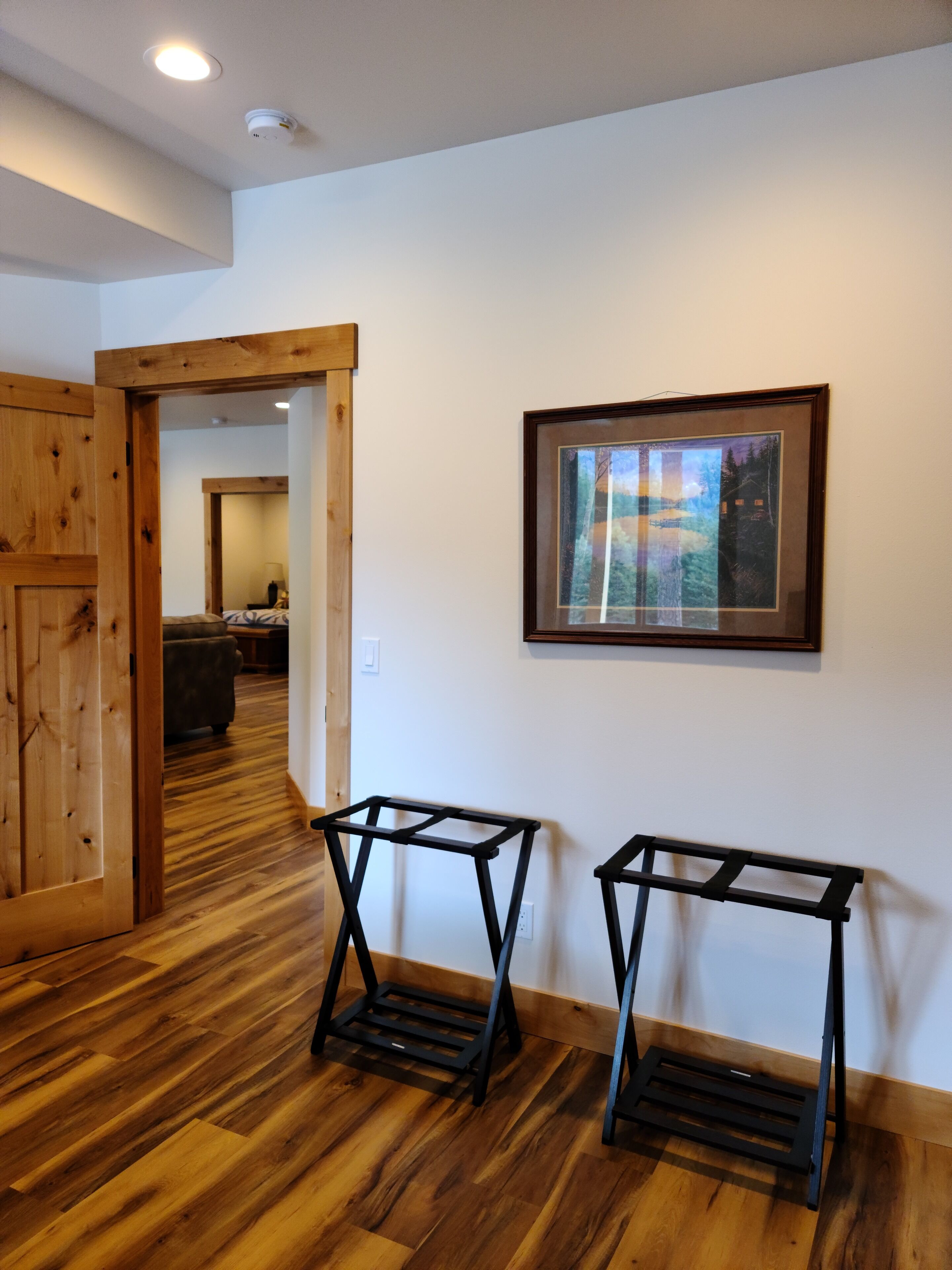 A room with wooden flooring, a framed picture on the wall, and two black metal stands.