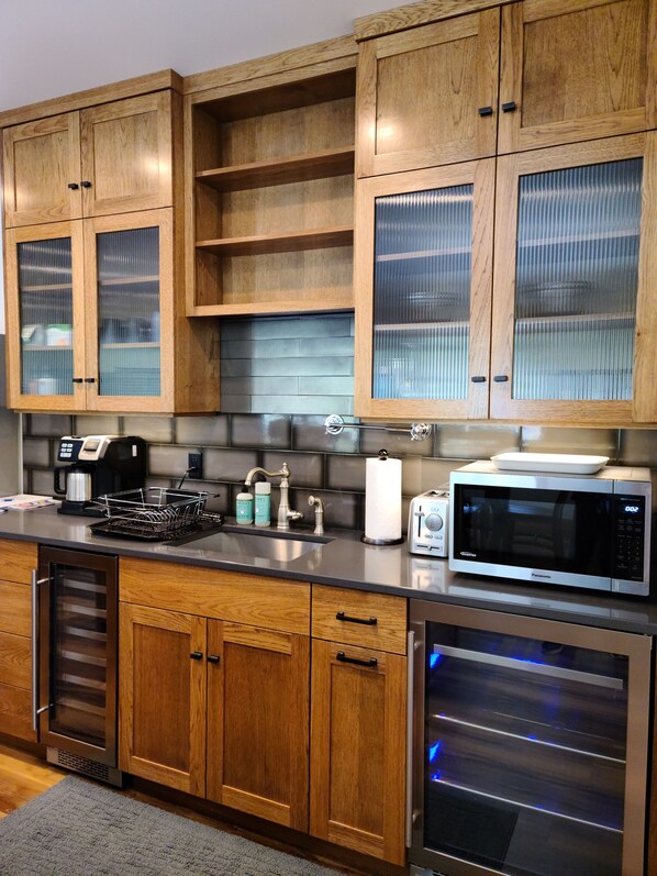 A modern kitchen with wooden cabinets, a stainless steel microwave, and a built-in oven.