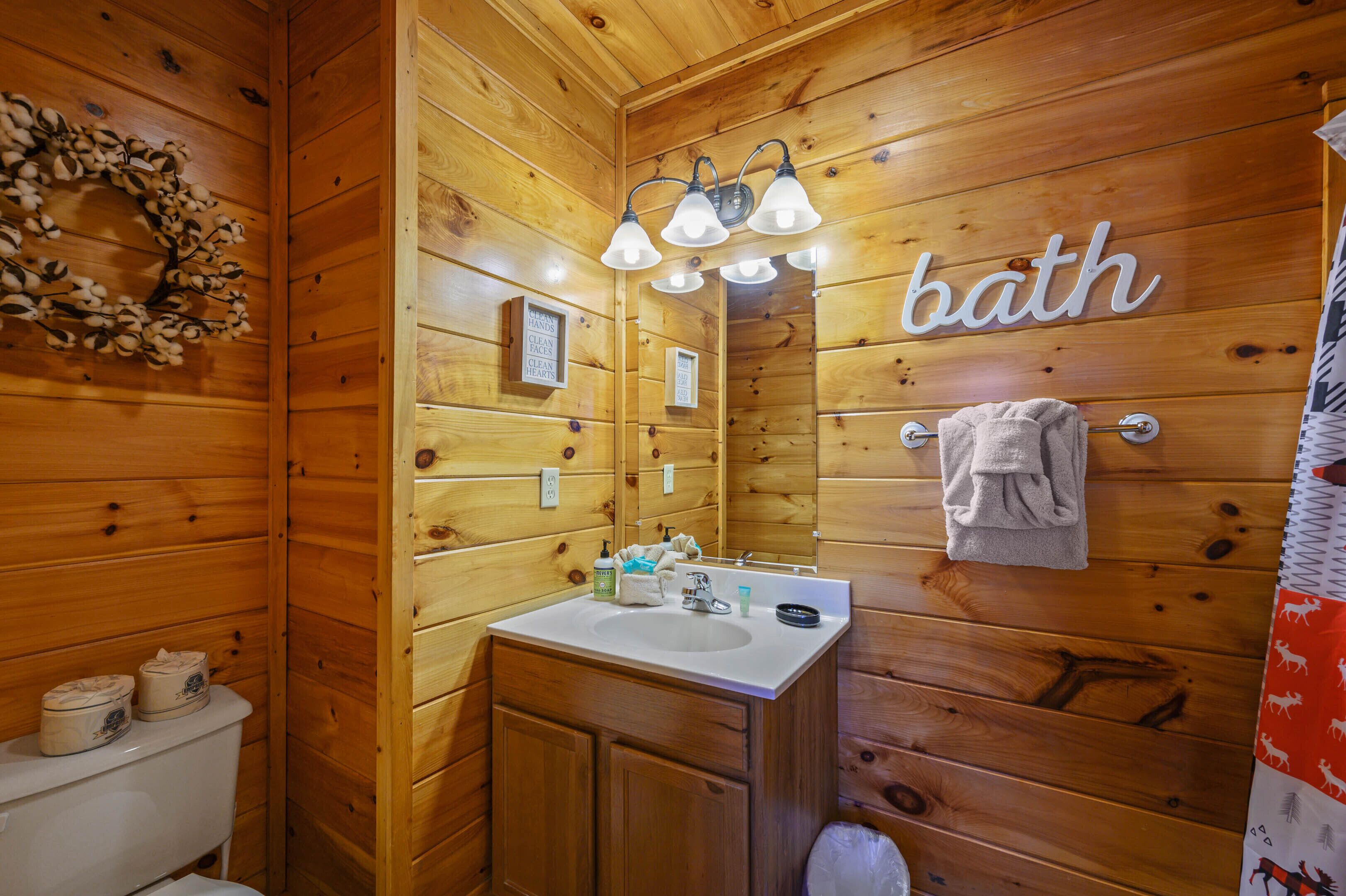 A wooden bathroom with a sink, mirror, and a 'bath' sign.