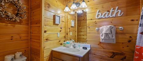 A wooden bathroom with a sink, mirror, and a 'bath' sign.