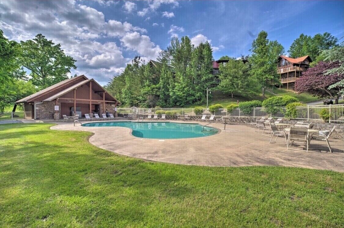 A pool area with lounge chairs, a stone building, and a wooden deck.