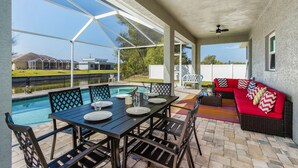 A covered patio with a pool, dining table, and outdoor seating area. - Waterfront Cape Coral Villa w/ Heated Pool, 4 Bedrooms, Pet-Friendly (Cape Coral)
