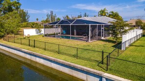 A house with a covered outdoor area and a swimming pool. - Waterfront Cape Coral Villa w/ Heated Pool, 4 Bedrooms, Pet-Friendly (Cape Coral)