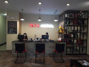 A reception desk with two chairs, a wall clock, and a sign that reads 'MJ's'. - MJ s Hotel (Jambi)