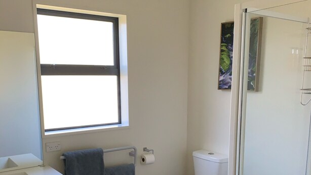 A modern bathroom with a toilet, sink, and shower. - Rural cottage (Tuamarina)