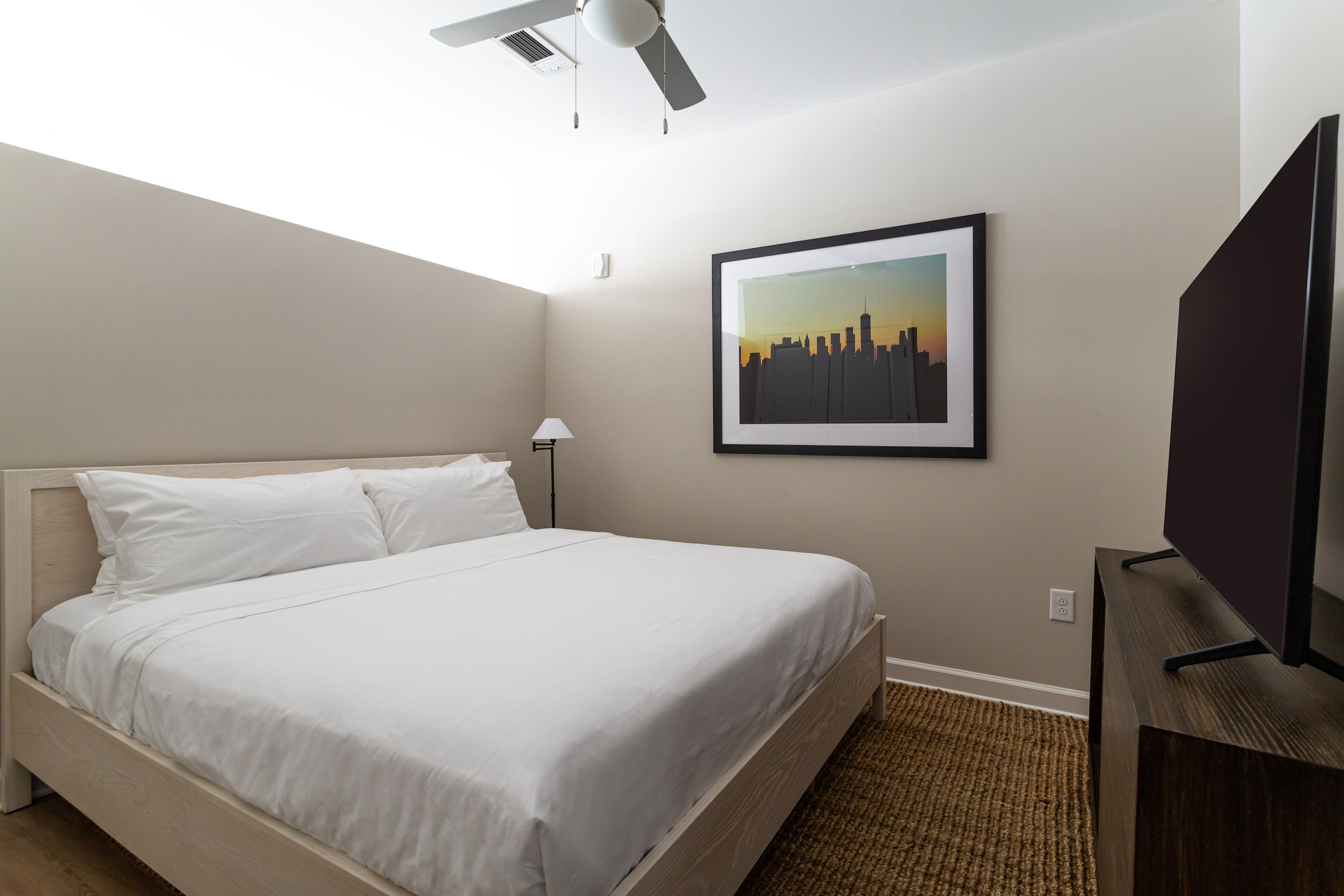 A neatly made bed with white linens in a hotel room.