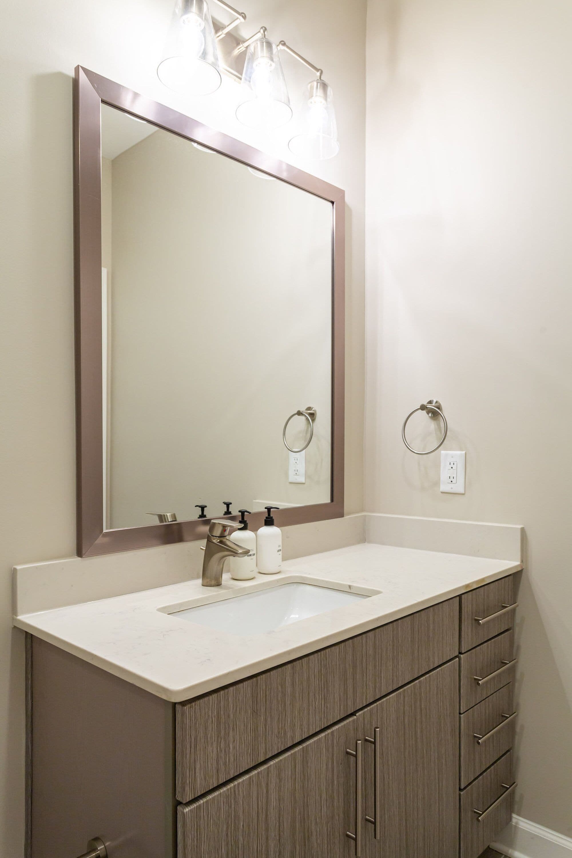 A bathroom with a large mirror, a sink, and a vanity with drawers.