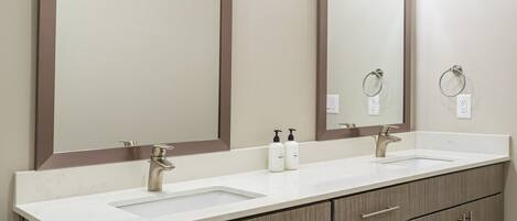 A bathroom with two sinks, a large mirror, and a vanity with drawers.