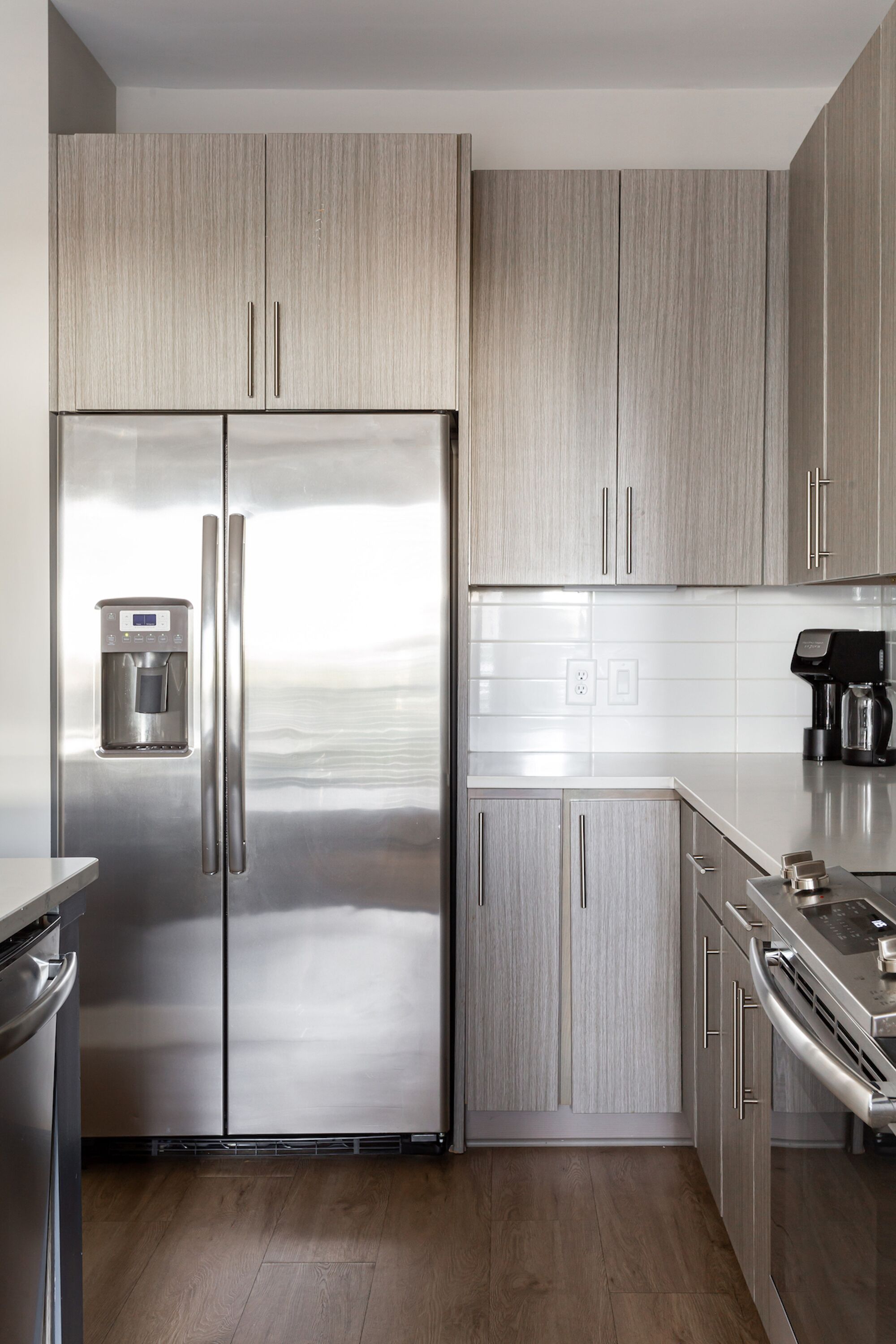Une cuisine moderne dotée d’appareils électroménagers en acier inoxydable, de meubles en bois et d’un distributeur d’eau intégré.