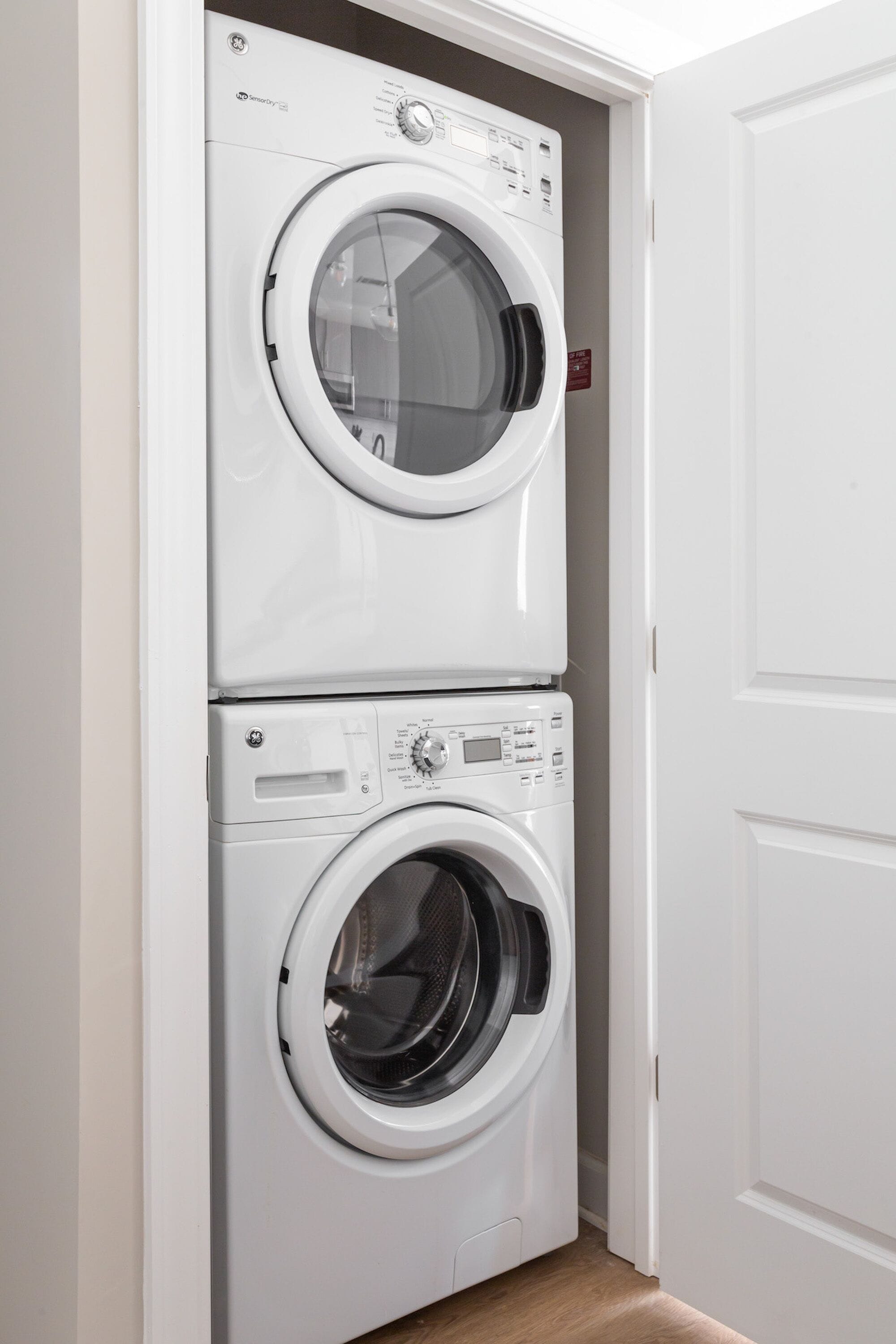 Une machine à laver et un sèche-linge superposés, installés dans un couloir.