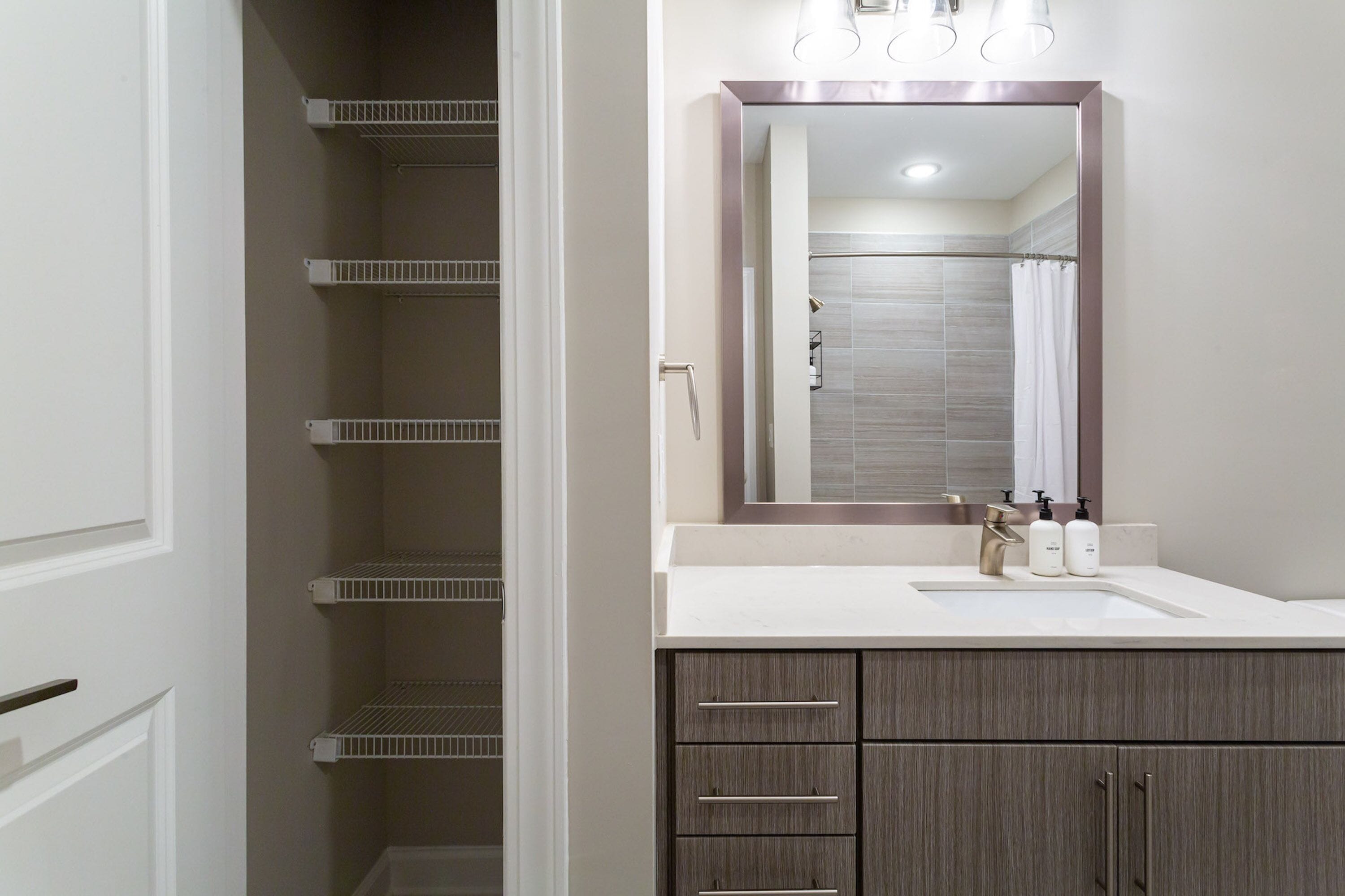A bathroom with a white sink, dark wooden cabinets, and a mirror with a light fixture above it.