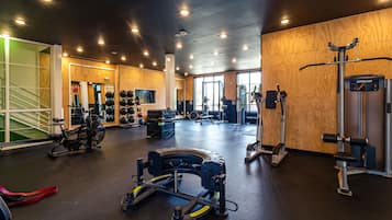 A gym with various exercise equipment, including a rowing machine, weight machines, and a pull-up bar.