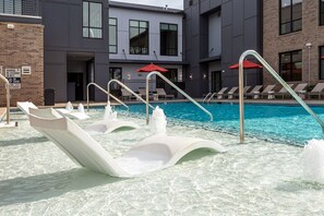 A pool area with lounge chairs and a water feature. - Kasa FreeMoreWest Charlotte (Charlotte)