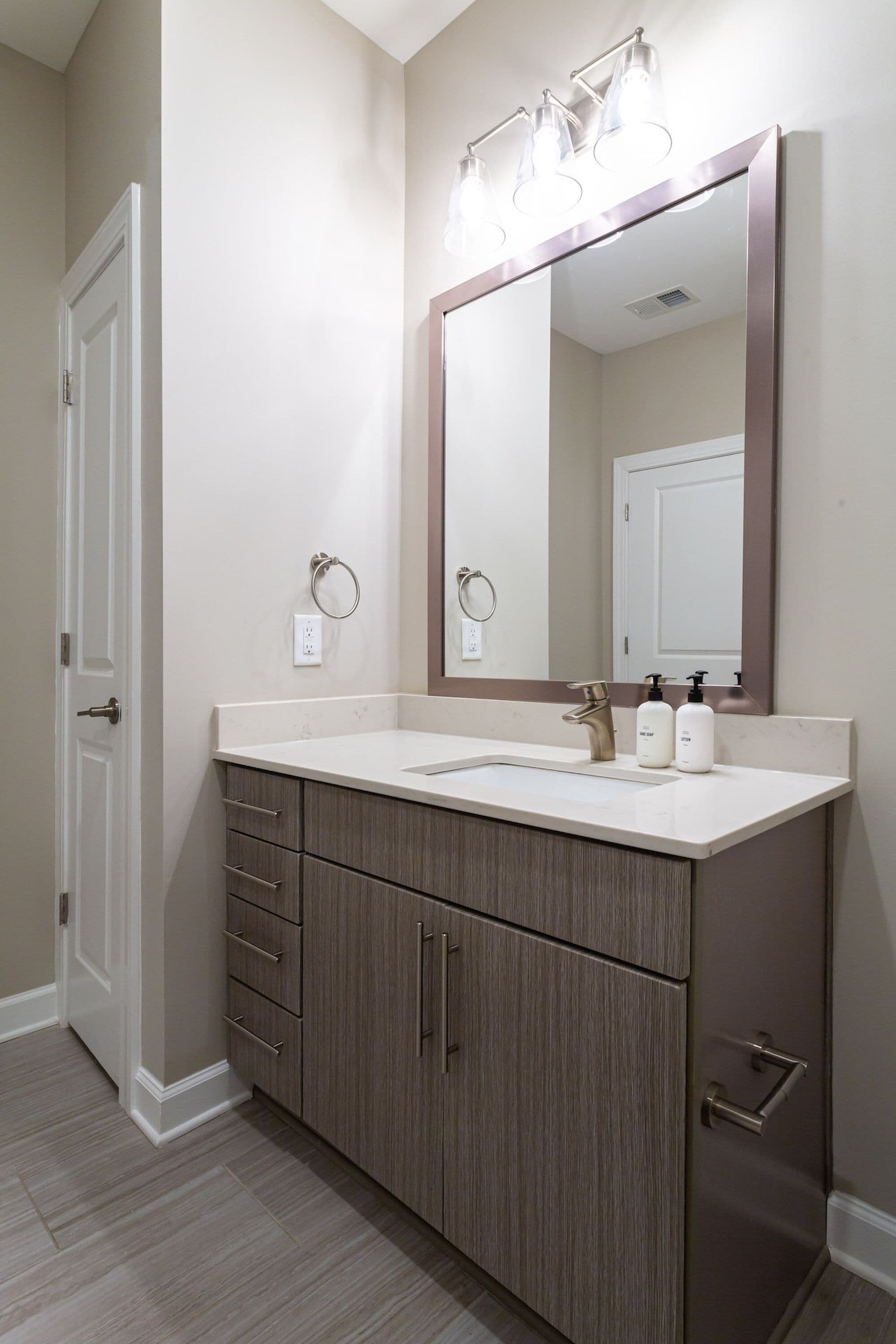 A bathroom with a double sink vanity, a large mirror, and a towel ring.