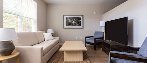 Un salon moderne avec un canapé, une table basse et un téléviseur.