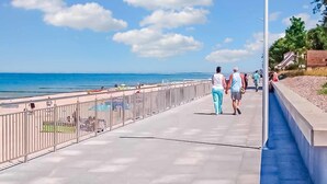 Un paseo marítimo con barandilla metálica, sendero de hormigón y vistas al mar.